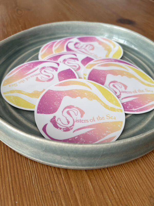 A green bowl with several coloured Sisters of the Sea stickers in it.