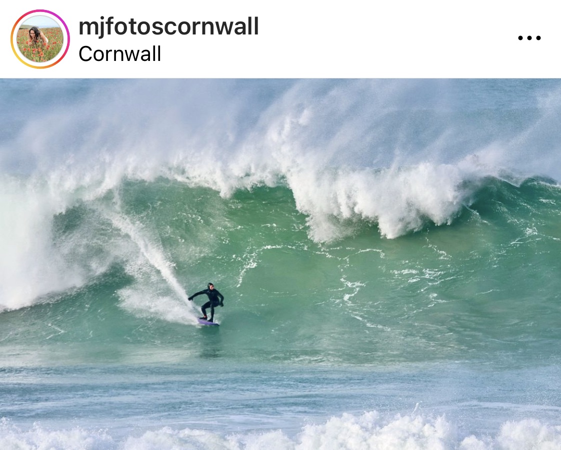 mjfotoscornwall instagram screenshot showing a surfer coming down a huge wave that crashes behind them.