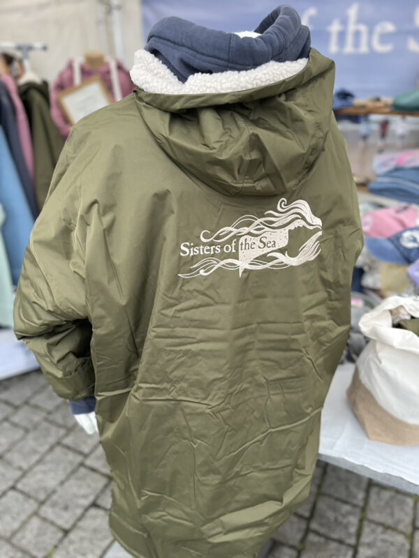 Back view of the Sisters of the Sea Everything Robe, an olive green change robe with a cream sherpa fleece lining and cream embroidered logo on the back.